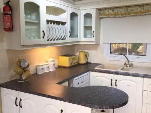 a kitchen with white cabinets and a black counter top at Pilgrims Rest 1 - Uk42662 in Ruan Major