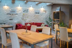 una sala da pranzo con tavoli, sedie e un divano di Dagen Haus Guesthouse a Orjaku