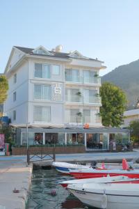 un grand bâtiment blanc avec des bateaux dans l'eau dans l'établissement Orka Boutique Hotel, à Fethiye