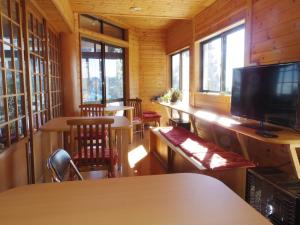 a room with tables and chairs and a flat screen tv at Shukubo Komadori-Sanso in Ome