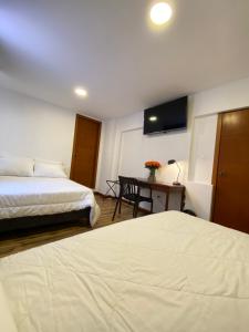 Pokój hotelowy z 2 łóżkami i biurkiem z telewizorem w obiekcie HOSTAL COMFORT- INN by BRILLIANT w mieście Quito