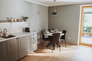 uma cozinha com uma mesa com cadeiras e uma sala de jantar em Upės apartamentai I su terasa ir baseinu em Anykščiai