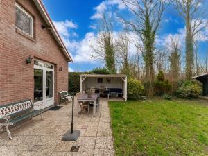 a patio with a table and a bench in a yard at Welcoming holiday home in Baarland with fenced garden in Baarland