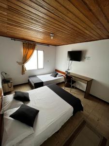 a bedroom with a large bed and a desk at Hotel Alpino in Armenia