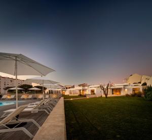 a row of lounge chairs next to a pool at night at Ericeira Prime Villas in Ericeira