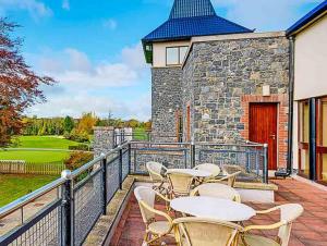 a patio with tables and chairs on a balcony at Great National Ballykisteen Golf Hotel in Tipperary