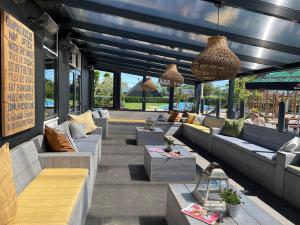 a outdoor patio with couches and tables and windows at Chalet (J10) op gezellige familiecamping bij zee in Kamperland