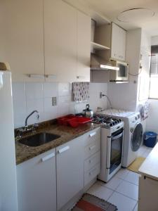 - une cuisine blanche avec évier et cuisinière dans l'établissement Apartamento completo em Cachoeira do Sul, à Cachoeira do Sul