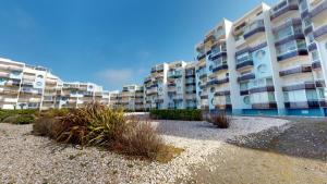 un gran edificio de apartamentos con algunas plantas delante de él en Appart Le Concorde en Saint-Gilles-Croix-de-Vie