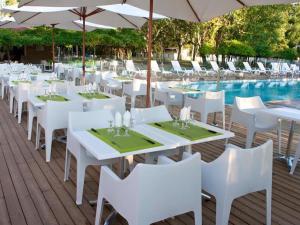 una fila de mesas y sillas blancas junto a una piscina en Camping U Casone - Maeva, en Ghisonaccia