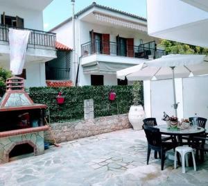 a patio with a table and an umbrella and a fireplace at Vasia's maisonette in Nea Fokea