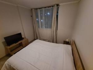1 dormitorio con cama blanca y ventana en Comodo y acogedor departamento, en Puerto Montt