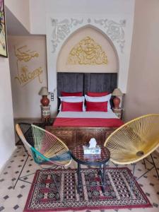 a bedroom with a bed and two chairs and a table at Riad Saida Atlas in Marrakesh