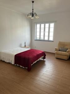 a bedroom with a bed and a couch and a window at Casa da Luz in Angra do Heroísmo