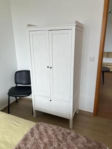 a white cabinet and a chair in a bedroom at Casa da Luz in Angra do Heroísmo