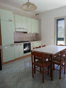 ガリポリにあるAppartamenti Gallipoli Lungomareの白いキャビネット、テーブルと椅子付きのキッチンが備わります。