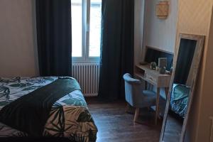 a bedroom with a bed and a desk and a window at Petite maison de bourg proche A84 in Ducey