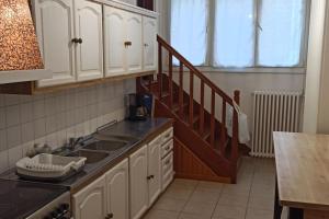 a kitchen with white cabinets and a sink and a staircase at Petite maison de bourg proche A84 in Ducey