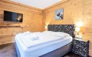ein Schlafzimmer mit einem großen weißen Bett an einer Holzwand in der Unterkunft Alpin & See Resort - Pinzgau Holidays in Zell am See