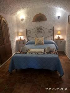 Hinojares的住宿－CASA CUEVA VANESA，一间卧室配有一张带蓝色床罩和两盏灯的床。