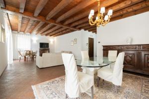 a dining room with a glass table and white chairs at Domus Verona - Centralissima e antica Residenza Cappello in Verona