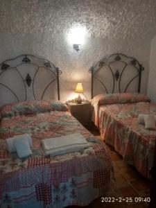 a bedroom with two beds and a table with a lamp at CASA CUEVA VANESA in Hinojares