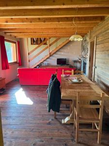 Habitación con mesa de madera y sofá rojo. en Baita “Oasi della Volpe” en Cà Paini
