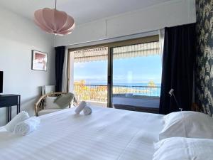 a bedroom with a large white bed and a large window at Le Garavan-vue mer-plage-clim-terrasse in Menton