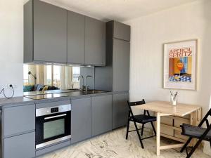 a kitchen with a table and a stove and cabinets at Le Garavan-vue mer-plage-clim-terrasse in Menton +9 photos