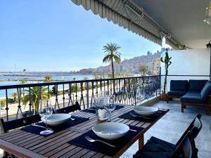 a wooden table with wine glasses on a balcony at Le Garavan-vue mer-plage-clim-terrasse in Menton