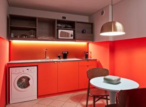 a red kitchen with a washing machine and a table at Urbanauts Studios Minelli in Trieste