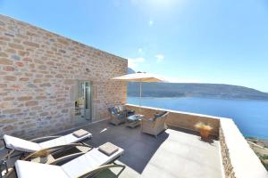 eine Terrasse mit Stühlen und einem Sonnenschirm neben dem Wasser in der Unterkunft Akrolithi Boutique Hotel & Suites in Itylo