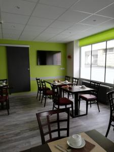 uma sala de jantar com mesas e cadeiras e paredes verdes em Hotel du Commerce em Cholet
