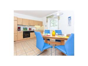 une cuisine avec une table en bois et des chaises bleues dans l'établissement Muschel 1, à Bensersiel