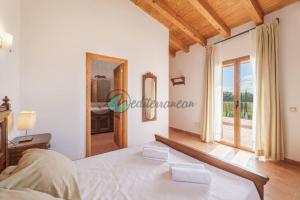 a bedroom with a bed and a large window at Ecovilla ses oliveres by villasmediterranean in Llubí