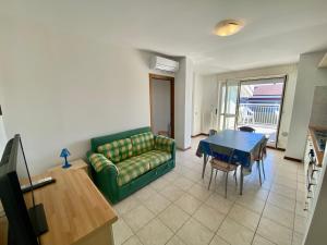 a living room with a green couch and a table at Appartamento Vista Mare con Spiaggia e Piscina in Alba Adriatica