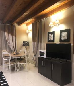 uma sala de estar com televisão e uma mesa com cadeiras em Villa Giotto Luxury Suite & Apartments em Mestre