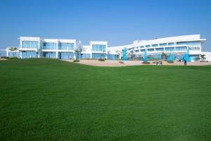 a large building with a green field in front of it at Zoya Health & Wellbeing Resort in Ajman 