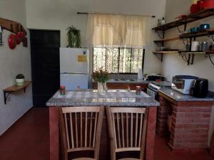 a kitchen with a counter with two chairs and a refrigerator at Casa de Alicia in Concepción de Ataco