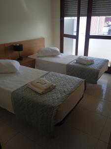 2 Betten in einem Hotelzimmer mit Handtüchern darauf in der Unterkunft Apartamento VI-ANA in Viana do Castelo