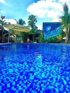 una gran piscina con azulejos azules frente a un edificio en Bến Đò Xưa Homestay & Coffee en Cái Răng