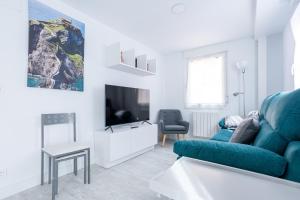salon z niebieską kanapą i telewizorem w obiekcie El Ancla de Bermeo By Urdaibai Rentals w mieście Bermeo +13 zdjęć