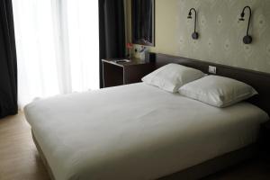 ein Schlafzimmer mit einem großen Bett mit weißer Bettwäsche und Kissen in der Unterkunft Hotel Corner House by WP Hotels in Blankenberge