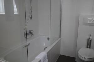 a white bathroom with a shower and a toilet at Hotel Corner House by WP Hotels in Blankenberge