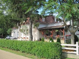 a house with a white fence in front of it at Göcsej Palatinus Étterem és Panzió in Zalaegerszeg