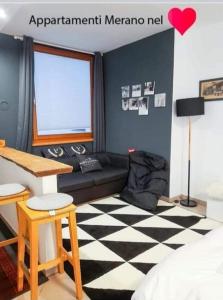 ein Wohnzimmer mit einem schwarzen Sofa und einem karierten Boden in der Unterkunft Appartamento Merano nel cuore in Meran