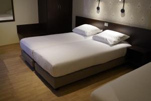 2 Betten in einem Hotelzimmer mit weißer Bettwäsche und Kissen in der Unterkunft Hotel Corner House by WP Hotels in Blankenberge