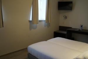 een slaapkamer met een wit bed en een raam bij Hotel Corner House by WP Hotels in Blankenberge