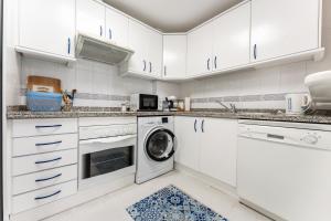 eine Küche mit weißen Schränken, einer Waschmaschine und einem Trockner in der Unterkunft Doña Sofía in Fuengirola