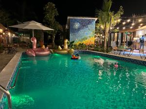 a swimming pool with inflatables in the water at night at Bến Đò Xưa Homestay & Coffee in Cái Răng